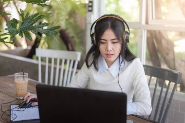 Kafede dizüstü bilgisayar ile çalışan genç Asyalı kadın