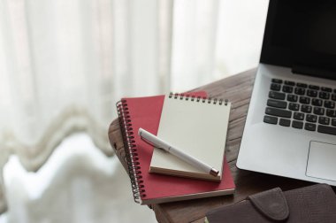 Ahşap masa üstünde defter ve laptop bilgisayar