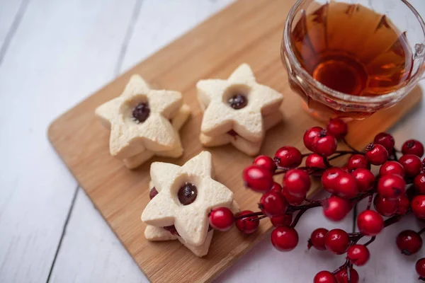 Christmas shortbread star cookies with strawberry jam. Festive atmosphere holiday pastry baking concept. Cookies and tea for Santa