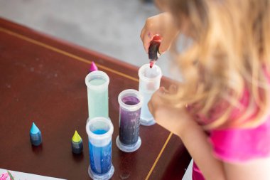 Yeni yürümeye başlayan bebek sanat projesi, dışarıda gıda boyası, test tüpleri ve suyla oynamak, erken yaşta öğrenmenin eğlenceli aktivitesi.