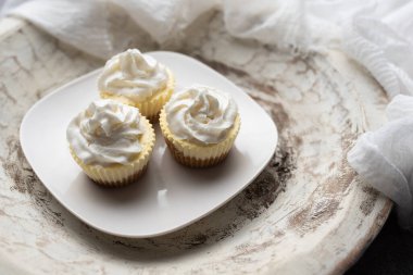 Beyaz tabakta krem şantili üç mini peynirli kek.