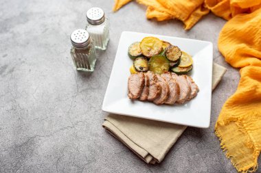 Kabak ve kabak çemberli bir tabakta dilimlenmiş domuz eti.
