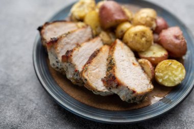 Baharatlı domuz rostosu ve kızarmış bebek patatesli parmesan. Bir tabağa yakın..