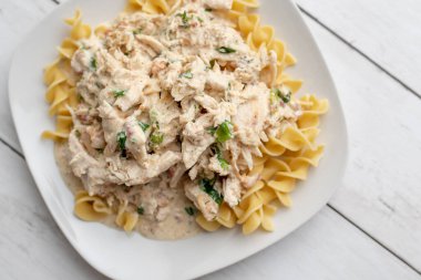 Kraker tavuğu yavaşça pişmiş beyaz tabakta yumurtalı makarna.