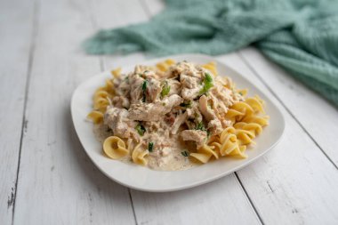 Kraker tavuğu yavaşça pişmiş beyaz tabakta yumurtalı makarna.