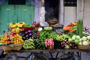 Indian street vendor with fresh vegetables and fruits along the road, Udaipur, India clipart
