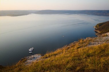 Dniester nehri tarafından yapılmış Bakota Körfezi manzarası. Kayalık kayalıklar ve gün batımında altın ışık. Suyun üstünde küçük yatlar. Ukrayna.