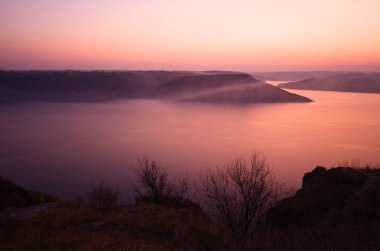 Gün batımında Bakota Körfezi 'nin pembe gökyüzü alacakaranlıkta. Dinyester nehrine büyük hidroelektrik barajı inşa edildikten sonra sular altında kalan eski köyün yerine yerleştirildi. Khmelnytskyi bölgesi, Ukrayna.
