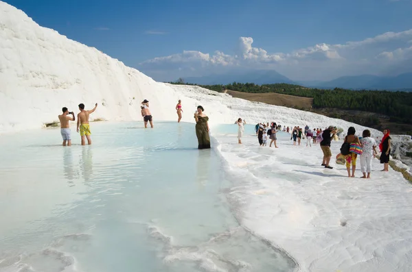 Pamukkale, Karahayit, Türkiye - Eylül 2018: Pamukkale 'nin beyaz geçitleri yakınlarında poz veren ve fotoğraf çeken turist kalabalığı. Mayolu insanlar sıcak termal suda banyo yapıyorlar.