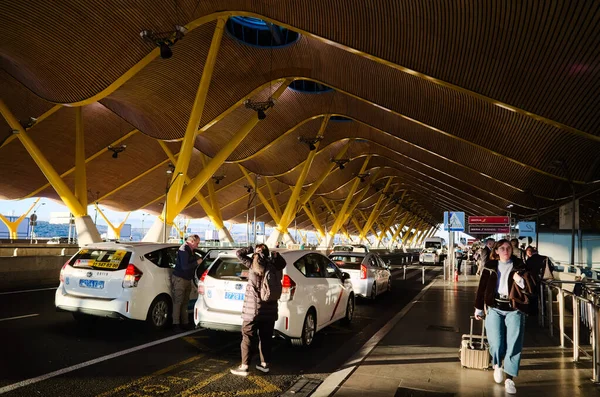 Madrid, Span - Ocak 2020: İnsanlar taksiyle Madrid Barajas Uluslararası Havalimanı 'na gitmek üzere park halindeyken ve bavullarıyla geliyorlar.. 