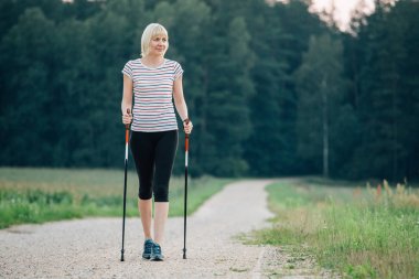 Nordik yürüyüş - aktif kadın açık egzersiz. Sarışın kız egzersiz forest yakınındaki. Macera ve egzersiz kavramı