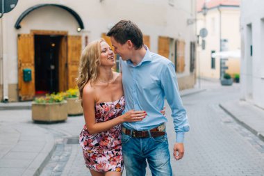 Sokakta yürürken sarılma genç mutlu çift. Gülümseyen adam ve neşeli kadın şehirde eğleniyor.