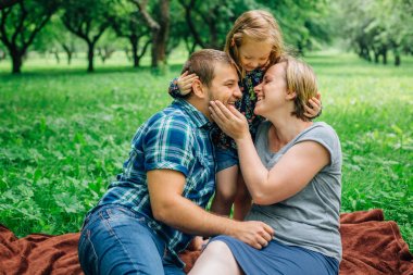 Üç battaniye parkta eğleniyor yatan genç mutlu aile. Mutlu anne-babalık kavramı. Annem ve babam açık havada küçük kızla