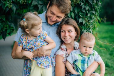 Parkta eğleniyor genç mutlu gülen bir aile. Güzel çocuklarını tutan anne. Çocuklar aşık Çift