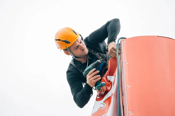 Industrial climber hangs a poster on a billboard