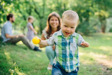 Parkta yürümeyi öğrenme şirin küçük oğlu. Mutlu anne gülen oğlu izlerken.