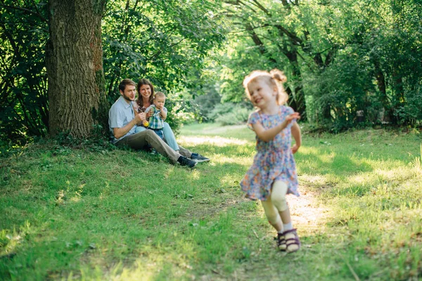 Jovem Família Feliz Brincando Parque Uma Menina Sorridente Fugir Dos — Fotografia de Stock