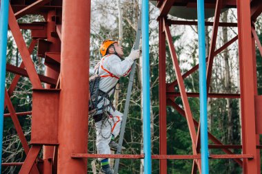 Endüstriyel dağcı üniforma ve kask yüksekliği açık havada üzerinde çalışıyor. Profesyonel çalışan su kulesi üzerinde yukarı tırmanma. 