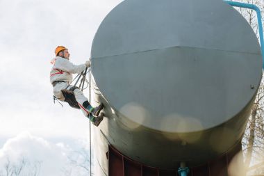 Endüstriyel dağcı üniforma ve kask yüksekliği açık havada üzerinde çalışıyor. Profesyonel çalışan su kulesi riskli onun işi. 