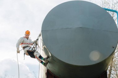 Endüstriyel dağcı üniforma ve kask yüksekliği açık havada üzerinde çalışıyor. Profesyonel çalışan su kulesi riskli onun işi. 