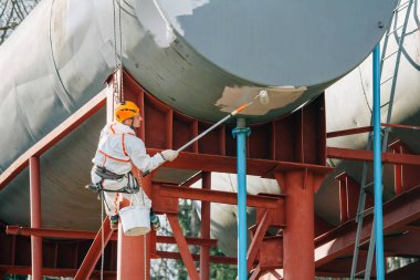 Endüstriyel dağcı kask ve Tekdüzen resim su kulesi. Profesyonel ressam yükseklik üzerinde çalışıyor. Riskli iş. Aşırı işgal.