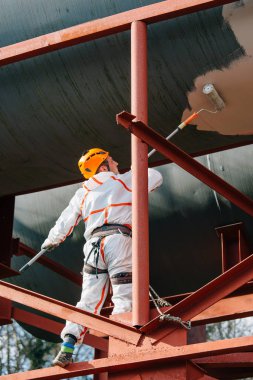 Endüstriyel dağcı kask ve Tekdüzen resim su kulesi. Profesyonel ressam yükseklik üzerinde çalışıyor. Riskli iş. Aşırı işgal.