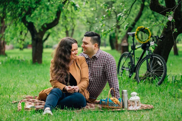 年轻的时尚幸福情侣在盛开的花园和自行车后面野餐 美丽的女孩和男人在户外约会 — 图库照片