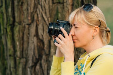 Kız ellerinde profesyonel kamera ile. Park kadın fotoğrafçı yakın çekim.