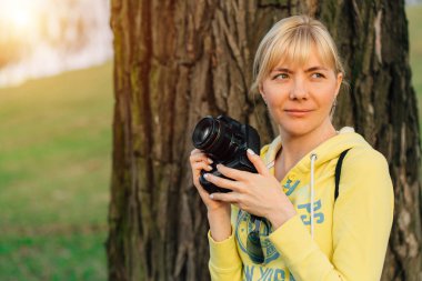 Kız ellerinde profesyonel kamera ile. Park kadın fotoğrafçı yakın çekim.