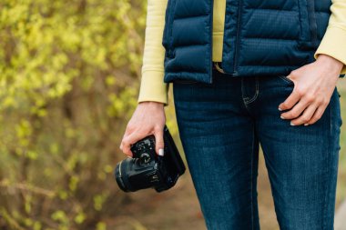Hor çiçeği bush ayakta eller profesyonel fotoğraf kızla. Park kadın fotoğrafçı yakın çekim.