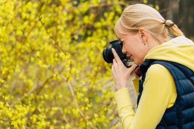 Hor çiçeği bush ayakta eller profesyonel fotoğraf kızla. Kadın fotoğrafçı fotoğraf park yaparken yakın çekim.