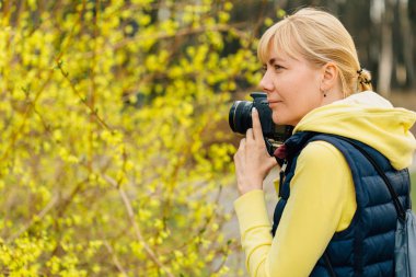 Hor çiçeği bush ayakta eller profesyonel fotoğraf kızla. Kadın fotoğrafçı fotoğraf park yaparken yakın çekim.