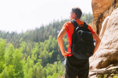 Sırt çantalı bir yürüyüşçü dağın tepesinde duruyor. Aktif sağlıklı yaşam tarzı macera seyahatleri.