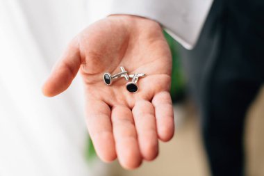 Damadın elindeki kol düğmelerini kapat. Düğün günü. Adam hazırlanıyor.