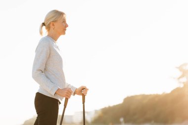 Sahilde İskandinav yürüyüşünden sonra dinlenen güzel genç bir kadın. Sağlıklı spor yaşam konsepti