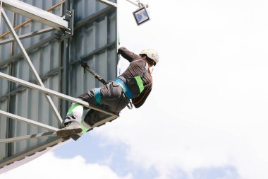 Miğferli ve boyuyla çalışan endüstriyel tırmanışçı. Riskli bir iş. Profesyonel işçi.