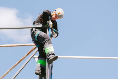 Miğferli ve boyuyla çalışan endüstriyel tırmanışçı. Riskli bir iş. Profesyonel işçi.