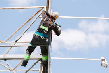 Miğferli ve boyuyla çalışan endüstriyel tırmanışçı. Riskli bir iş. Profesyonel işçi.