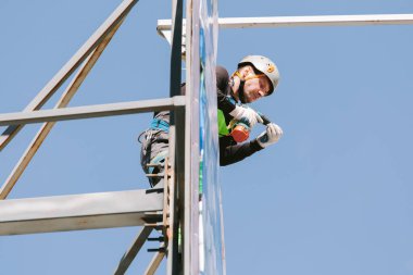 Miğferli ve boyuyla çalışan endüstriyel tırmanışçı. Riskli bir iş. Profesyonel işçi.