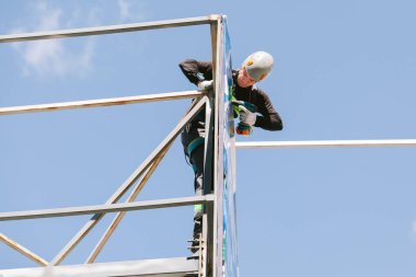 Miğferli ve boyuyla çalışan endüstriyel tırmanışçı. Riskli bir iş. Profesyonel işçi.