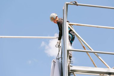 Miğferli ve boyuyla çalışan endüstriyel tırmanışçı. Riskli bir iş. Profesyonel işçi.