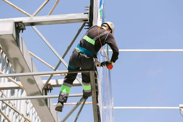 Industrial climber in helmet and overall working on height. Risky job. Professional worker