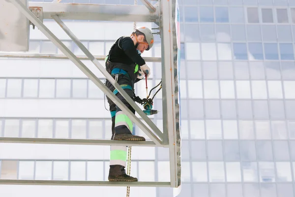 Industrial climber in helmet and overall working on height. Risky job