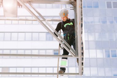 Miğferli ve boyuyla çalışan endüstriyel tırmanışçı. Riskli bir iş. Profesyonel işçi.