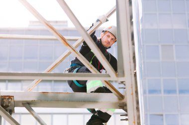 Miğferli ve boyuyla çalışan endüstriyel tırmanışçı. Riskli bir iş. Profesyonel işçi.