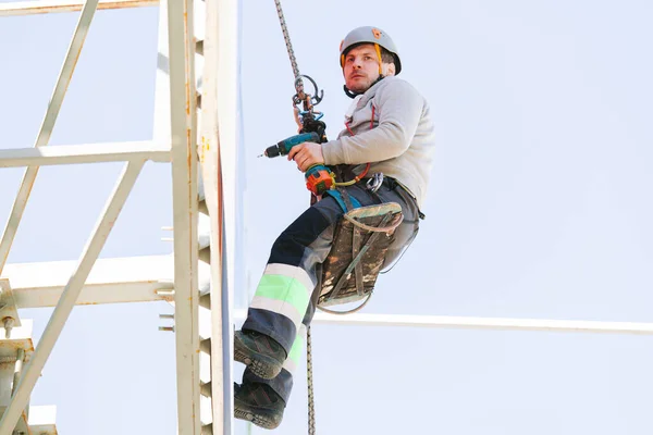 Industrial climber in helmet and overall working on height. Risky job. Professional worker