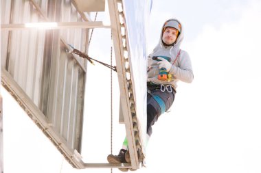 Miğferli ve boyuyla çalışan endüstriyel tırmanışçı. Riskli bir iş. Profesyonel işçi.