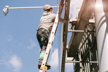 Miğferli ve boyuyla çalışan endüstriyel tırmanışçı. Riskli bir iş. Profesyonel işçi.