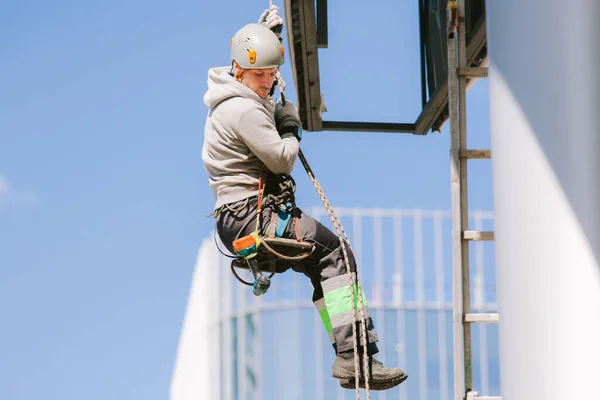 Industrial climber in helmet and overall working on height. Risky job. Professional worker