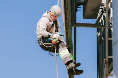 Miğferli ve boyuyla çalışan endüstriyel tırmanışçı. Riskli bir iş. Profesyonel işçi.